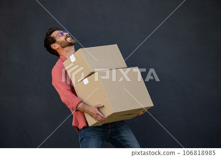 Contented young man with heavy carton boxes in hands Contented young man with heavy carton boxes in hands 106818985