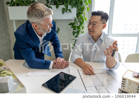 Men architects working on construction plans, engineers discussing on project in office. 106819044