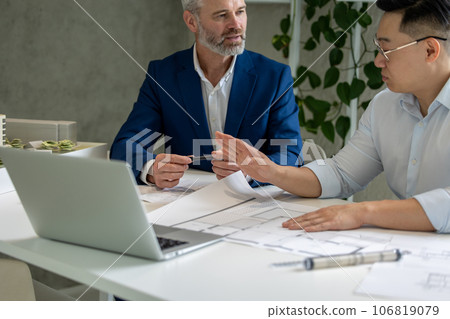 Men architects working on construction plans, engineers discussing on project in office. Men architects working on construction plans, engineers discussing on project in office. 106819079