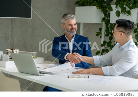 Architects working on construction plans, engineers discussing on project, handshaking, deal. 106819083