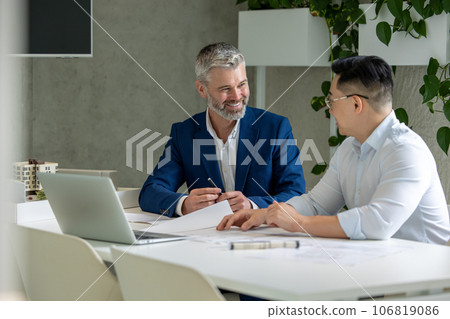 Men architects working on construction plans, engineers discussing on project in office. 106819086