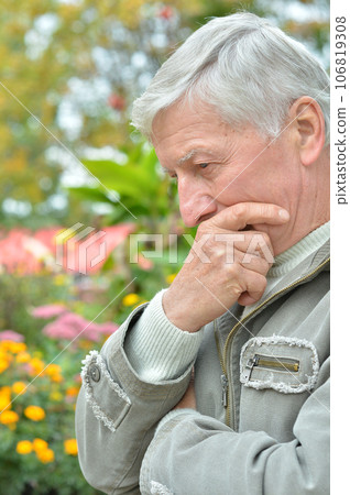 Serious senior man thinking in park on green background Serious senior man thinking in park on green background 106819308
