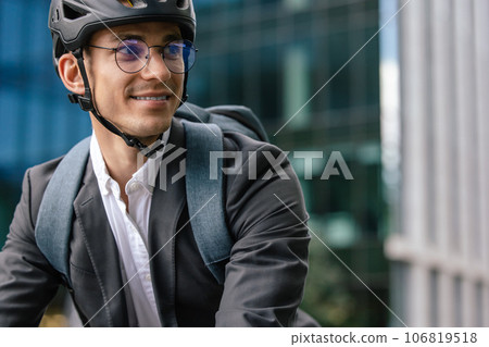 Smiling young businessman in helet riding a bike Smiling young businessman in helet riding a bike 106819518