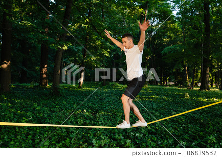 Young man in white tshirt walking on the rope Young man in white tshirt walking on the rope 106819532