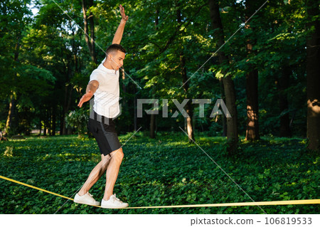 Young man in white tshirt walking on the rope Young man in white tshirt walking on the rope 106819533