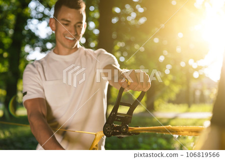 Young smiling man in the forest practising slacklining Young smiling man in the forest practising slacklining 106819566