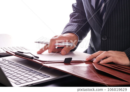 A man in a suit seriously checking documents A man in a suit seriously checking documents 106819629