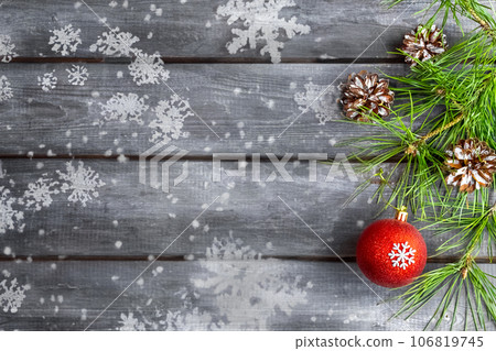 Christmas card. A spruce branch with a red decorative ball and cones on a wooden background. Place for text Christmas card. A spruce branch with a red decorative ball and cones on a wooden background. Place for text 106819745