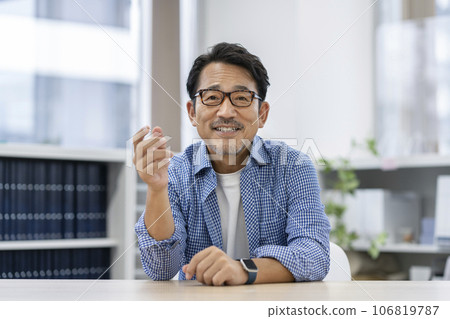 A man in his 50s wearing glasses talking looking at the camera 106819787