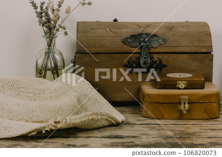 Antique wooden boxes and a vase of dry wildflowers on an old table. Rustic still life with memory about the past. Rusty style chest walnut box for jewelry. Magical faded background. Pirates theme. 106820073