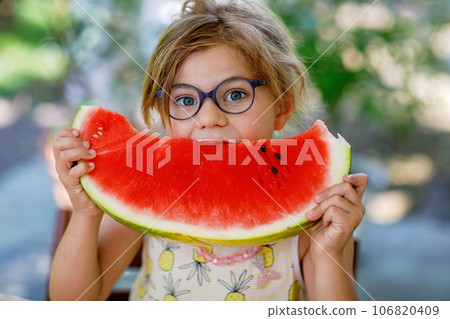 Little Girl, Preschooler, Delights in a Juicy Watermelon on a Sunny Summer Day. Child sharing a Healthy Snack with Her Family, She Embraces the Joy of Summertime Bliss 106820409