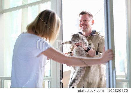 Man giving grey cat to woman through door 106820870