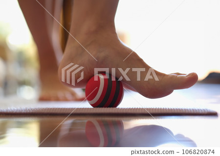 Person rolls massage ball with foot of foot closeup 106820874