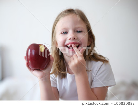 Portrait of joyful child girl without teeth holds apple Portrait of joyful child girl without teeth holds apple 106820882