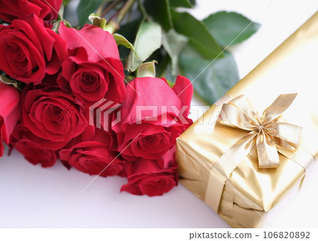Gift box for Valentine Day tied with golden satin ribbon bow and beautiful roses 106820892