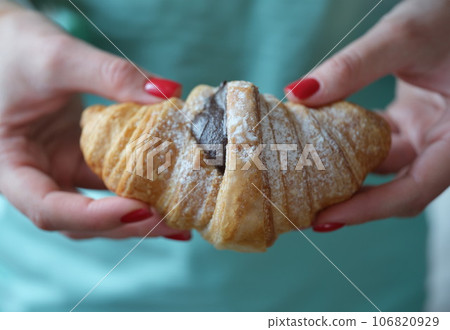 Cropped view of woman holding fresh croissant with chocolate 106820929