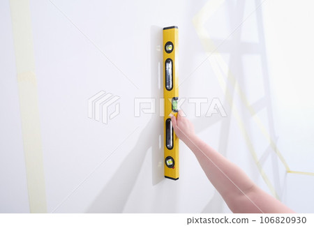Person checks slope of wall with a water level closeup Person checks slope of wall with a water level closeup 106820930