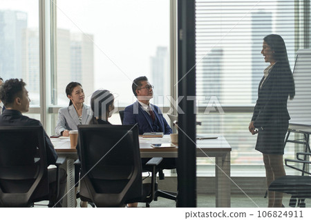 young asian businesswoman speaking to team of businesspeople in meeting in conference room 106824911