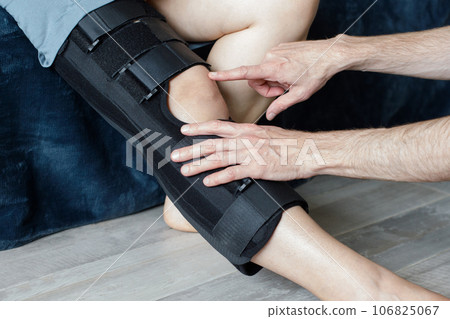 Therapist fitting a knee brace to patient leg Therapist fitting a knee brace to patient leg 106825067
