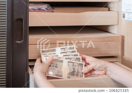 [A housewife hiding a wad of money in a Japanese dresser] 106825385