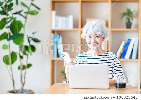 一位年長的女士在客廳裡進行遠程辦公。 一位年長的女士在客廳裡進行遠程辦公。 106825643