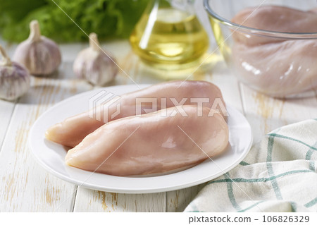 Raw chicken breast with salt, garlic and fresh herbs on a white table. Healthy food. 106826329