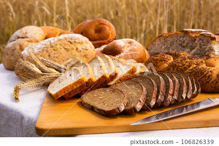 Lot of different flavored bread, wheat, rye, on the table in the field outside Lot of different flavored bread, wheat, rye, on the table in the field outside 106826339