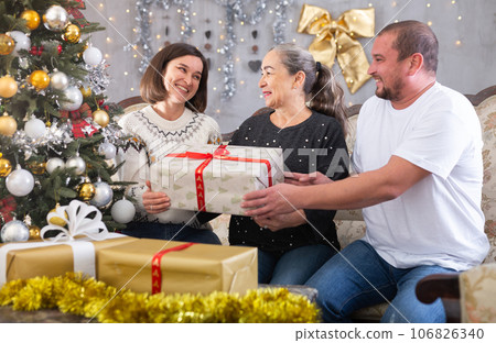 Family holding gifts on sofa in christmas interior 106826340