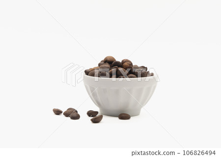 coffee beans in a white bowl and scattered on the isolated background coffee beans in a white bowl and scattered on the isolated background 106826494