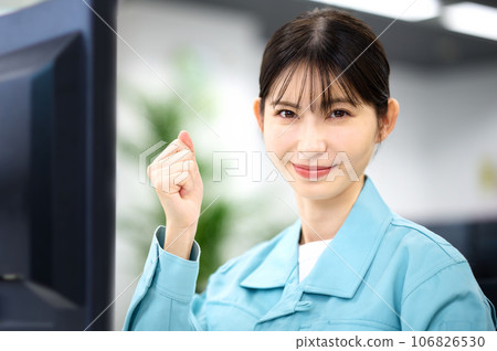 A woman wearing work clothes operating a computer 106826530