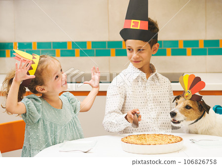 Cute girl showing how big her piece of Thanksgiving apple pie should be. Children wearing party hats eating holiday cake 106826758