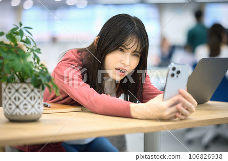 A woman operating a smartphone in a coworking space A woman operating a smartphone in a coworking space 106826938