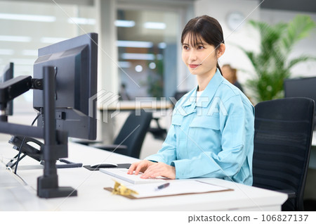A woman wearing work clothes operating a computer A woman wearing work clothes operating a computer 106827137