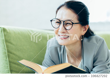 Portrait of a senior woman reading on a sofa 106827202