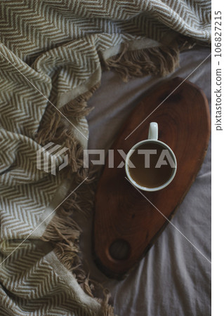 Cup of coffee on wooden tray with warm plaid. Flat lay, top view. Cozy autumn or winter home still life. Breakfast in bed 106827215