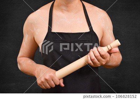 Cropped view of male chef with roller pin on black background. Hold rolling pin for dough. 106828152