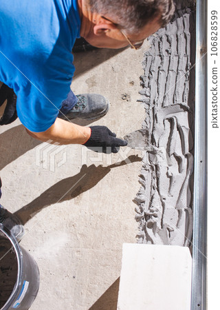 Happy smiling construction worker constructing or building wall by placing bricks and cement - concept of hard working, manual labour and daily wagers lifestyle Happy smiling construction worker constructing or building wall by placing bricks and cement - concept of hard working, manual labour and daily wagers lifestyle 106828599