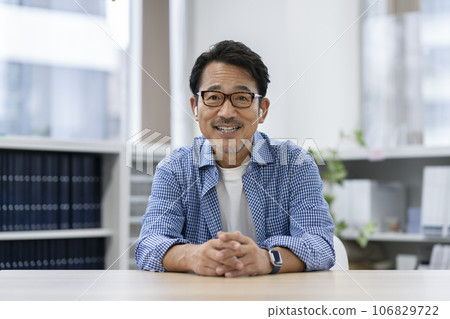 A man in his 50s wearing earphones looking at the camera 106829722