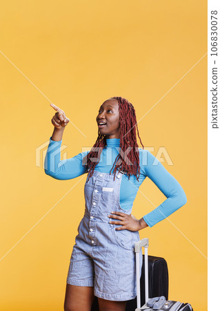 Young adult sightseeing on vacation trip in studio, looking at architecture on scenic route. Joyful woman pointing at buildings and landmarks on cityscape, having fun on adventure. 106830078