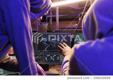 Hackers spying online and checking confidential data on computer screen. Two criminals in hoods collaborating, attacking on server password and gathering sensitive information Hackers spying online and checking confidential data on computer screen. Two criminals in hoods collaborating, attacking on server password and gathering sensitive information 106830099