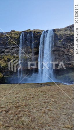 Majestic icelandic cascade in nordic region with water stream falling off frosty edges, seljalandsfoss waterfall with river. Beautiful landscape within nordic wilderness, frozen land in iceland. 106830141