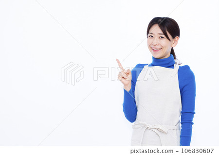 A housewife in her thirties who raises her index finger in front of a white background 106830607