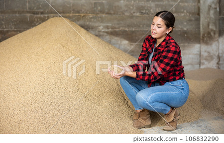 Positive female farmer with handful of feed calf feed in her hands 106832290