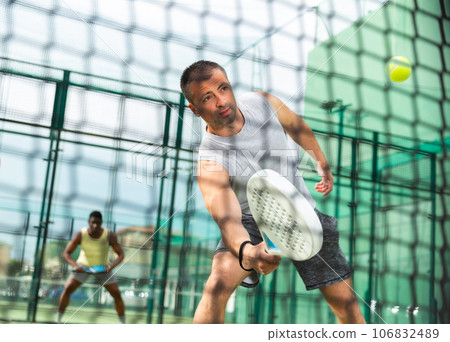 Athletic mens plays padel. View through tennis net 106832489