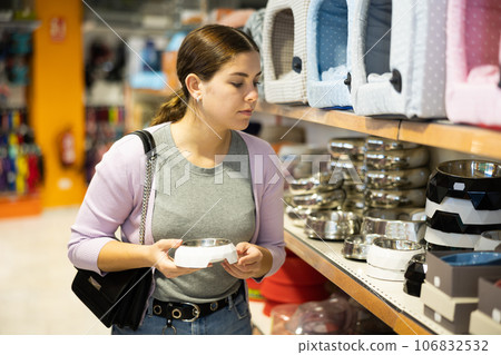 Young happy woman choosing bowl for pets in pet shop 106832532