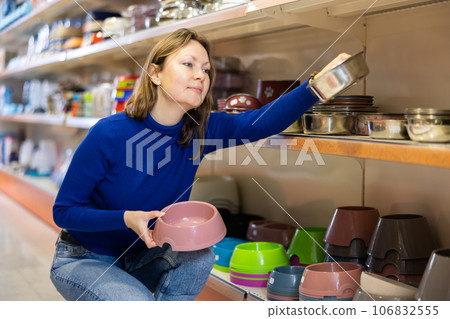 Young woman looking for food bowl for dog in pet store 106832555
