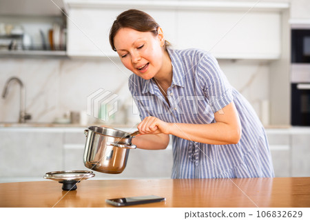 Inexperienced housewife holds saucepan in hands and calls asking for cooking advice Inexperienced housewife holds saucepan in hands and calls asking for cooking advice 106832629