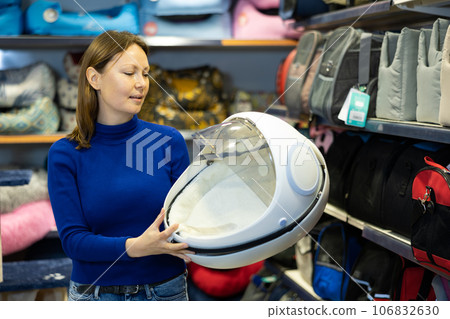 Woman choosing plastic pet carrier bag for cats in pet shop Woman choosing plastic pet carrier bag for cats in pet shop 106832630