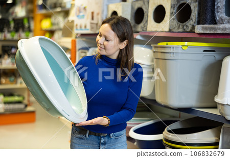 Confident woman choosing plastic litterbox for cats in pet shop 106832679