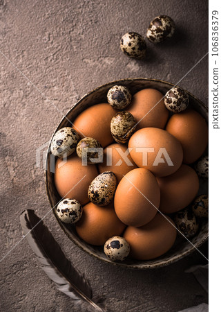 Chicken and quail eggs on brown background Chicken and quail eggs on brown background 106836379